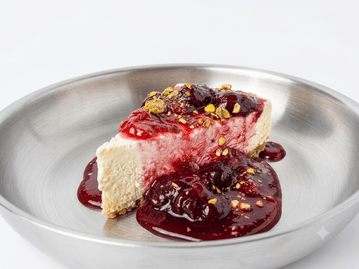 Fatia de cheesecake com calda de frutas vermelhas em prato de metal