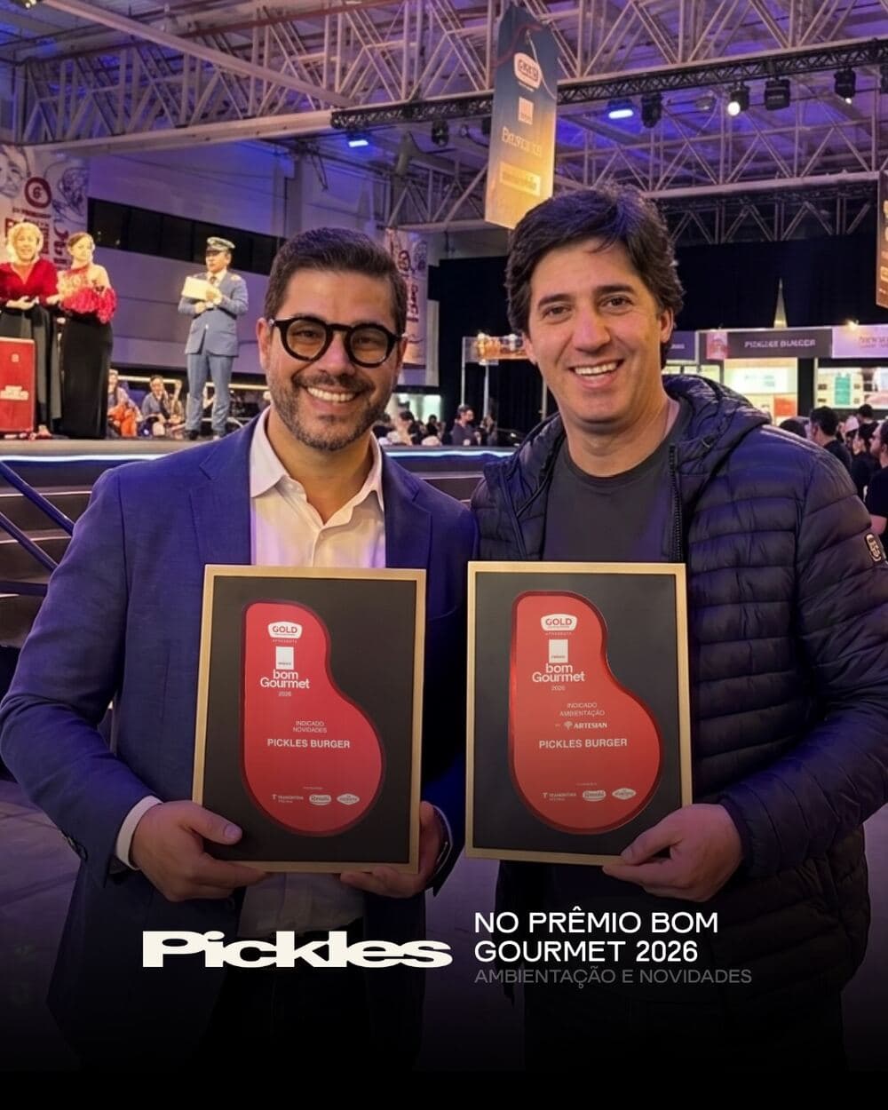 Os dois sócios do Pickles Burger lado a lado, cada um segurando uma placa de reconhecimento